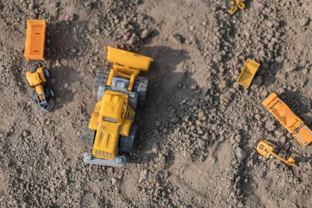 Photo of Plastic Truck toys in a sand outdoors.