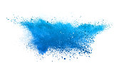 Blue powder explosion. The particles of charcoal splatter on white background. Closeup of colored dust particles splash isolated on background.