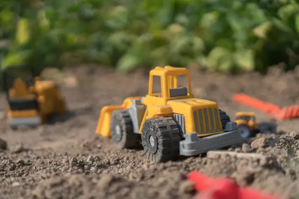 Photo of Plastic Truck toys in a sand outdoors.