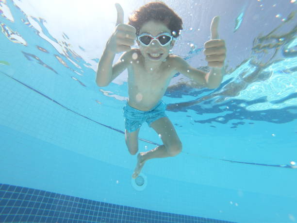 istock Boy swimming underwater in swimming pool 1037651662