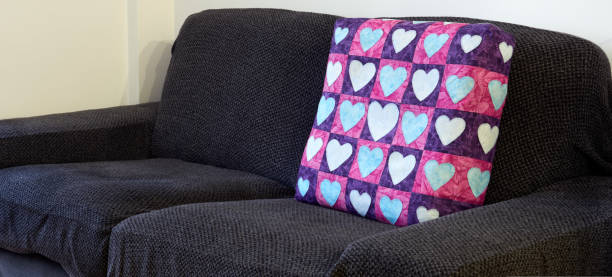 istock Empty sofa with purple and pink pillow covered in heart-form patches 1037656642