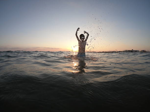 Happy boy swimming on the sea making splash