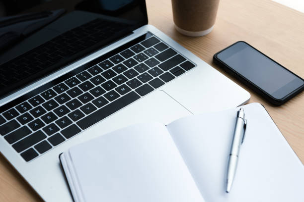 istock laptop, smartphone and blank notebook with pen on wooden table 1037679878