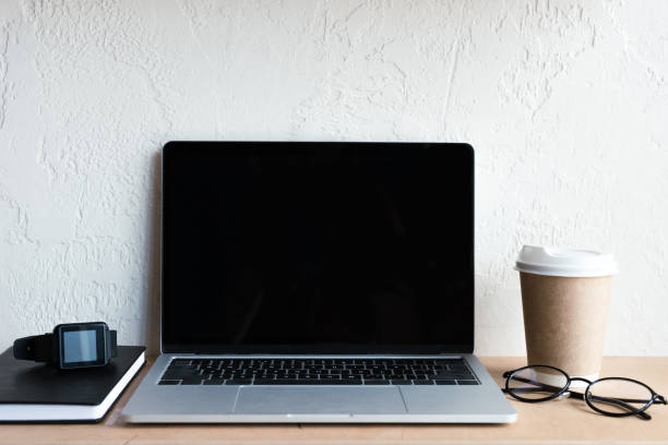 istock laptop with blank screen, smartwatch, notebook, eyeglasses and coffee to go on table 1037679938