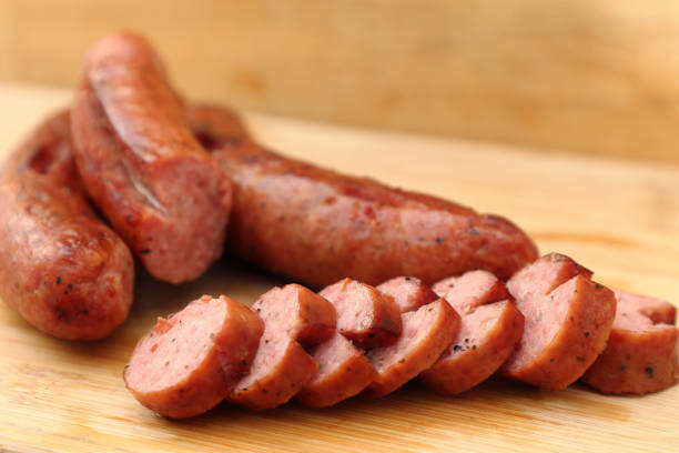 sliced grilled sausage on a table A picture of the smoked sausage sliced on the wooden table. The front row of sausage slices are in-focus. main course stock pictures, royalty-free photos & images