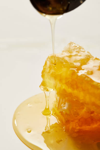 istock close up view of beeswax and pouring honey process on white backdrop 1037699554