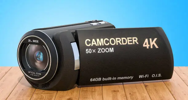 Camcorder, videocamera on the wooden desk. 3D rendering