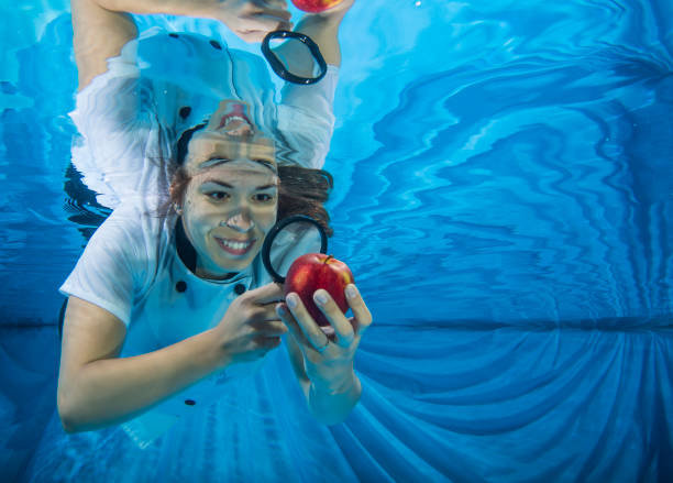 Young female girl  swimming with a red apple and a magnifoer