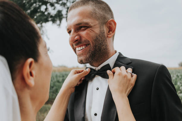 befestigung des bräutigams bowtie bei einer hochzeit - wedding newlywed bride couple stock-fotos und bilder