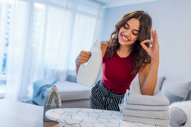 hermosa joven sostiene a una tela de suavizante de telas y toallas limpias - cleaning domestic kitchen counter top housework fotografías e imágenes de stock