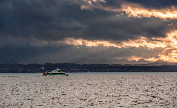 Ship rides on the lake Bodensee on a cold day of November at sunset with the alps in the background