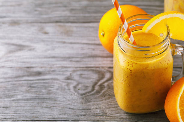 istock Vitamin drink: smoothies from fresh oranges in a glass jar on a wooden table with space for text, close-up 1037742940