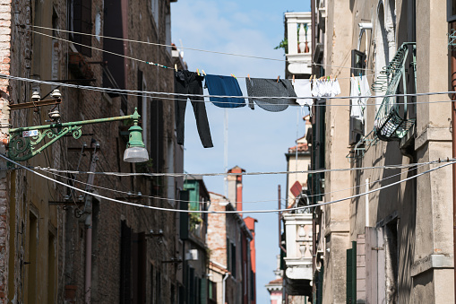 Drying underwear hanging on the ropes near walls of antique buildings in Venice on a sunny day