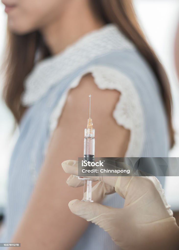 Immunization and vaccination for polio, flu shot, influenza or HPV prevention with woman having vaccine shot with syringe by nurse for World immunization week and International HPV awareness day Vaccination Stock Photo