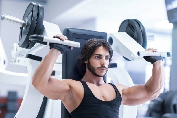 Bodybuilder working out with shoulder press machine stock photo