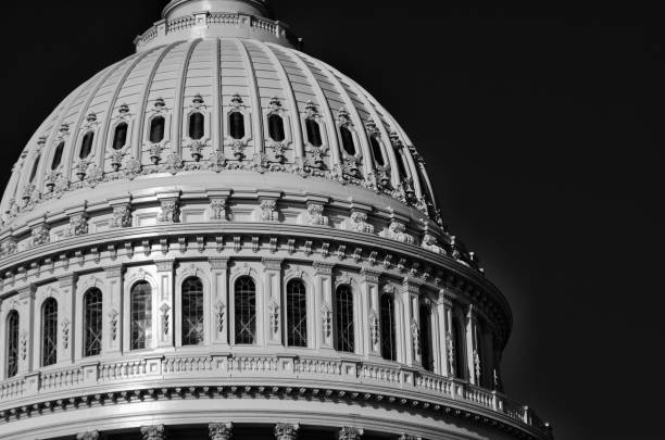Bright morning close-up of the shiny marble exterior of the US Capitol government building in black and white against dark sky