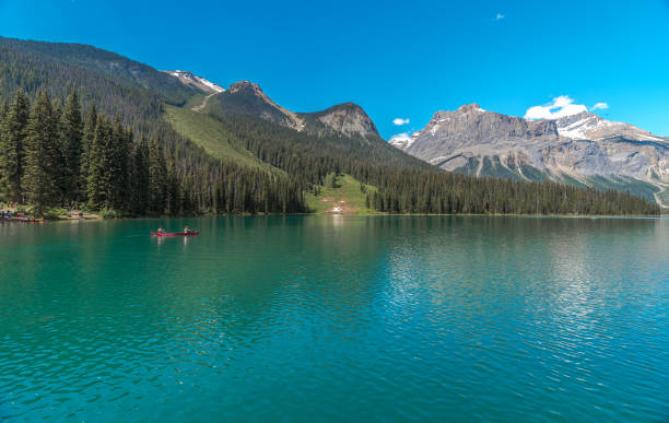 istock Canoe Crossing Emerald Lake against Snowcapped Mountains 1037835562