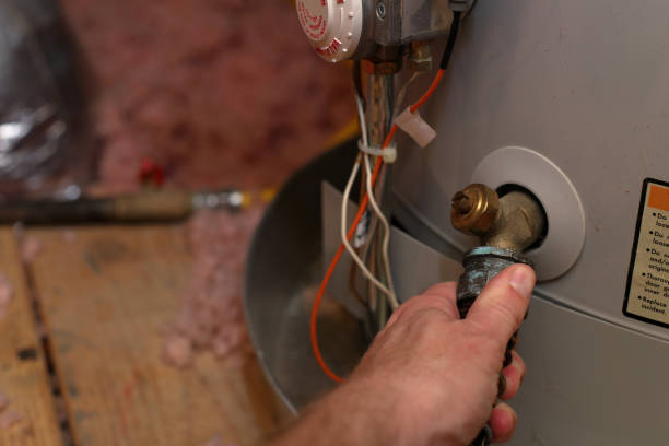 Hand attaches hose to water heater in home stock photo