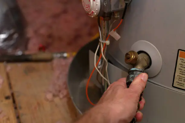 Photo of Hand attaches hose to water heater in home