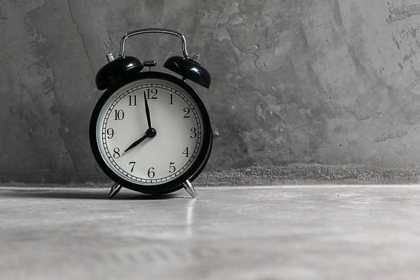 istock Black Alarm Clock on cement floor and background 1037895354