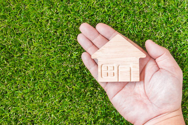 istock Home shaped on Man's hand over green grass. Green Home Concept. 1037895404