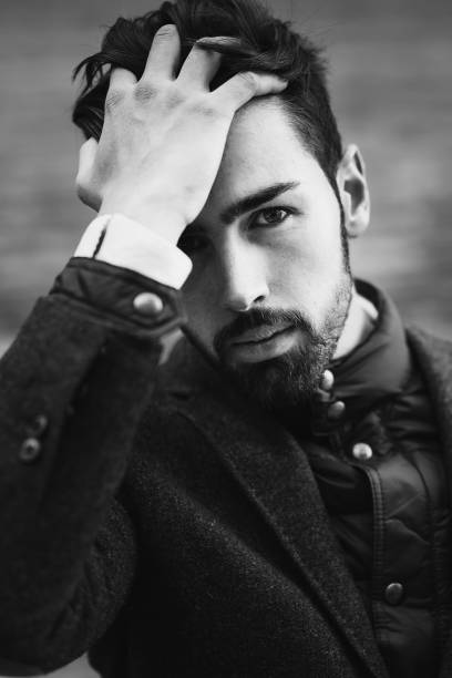 istock Young bearded man wearing british elegant suit touching his hair 1037903314