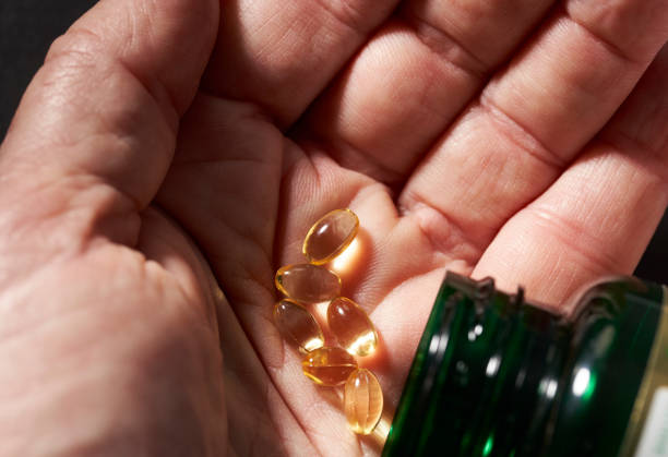 vitamine in der hand mit glas - capsule gel effect pill vitamin pill stock-fotos und bilder