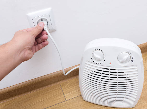 istock Person's hand plug in electric heater in the socket. 1037951722