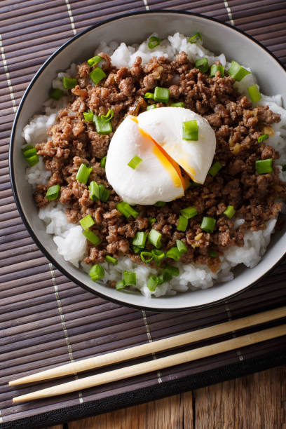 istock Japanese dish: spicy meat Soboro with egg poached and rice close-up in a bowl.Vertical top view 1037984334