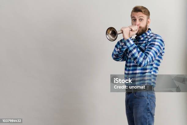 Funny Bearded Man In A Plaid Shirt Blowing Into The Copper Horn Stock Photo  - Download Image Now - iStock