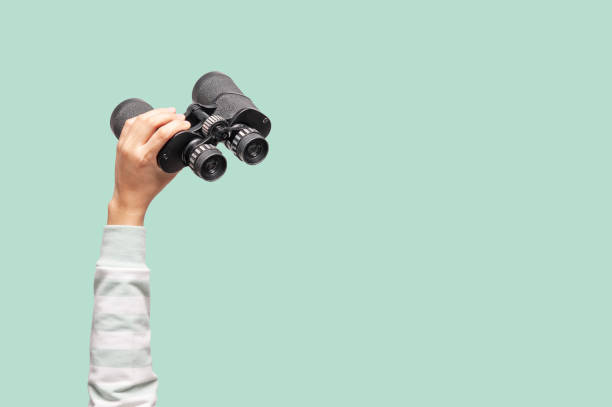 mujer con prismáticos en fondo verde - binaculars fotografías e imágenes de stock