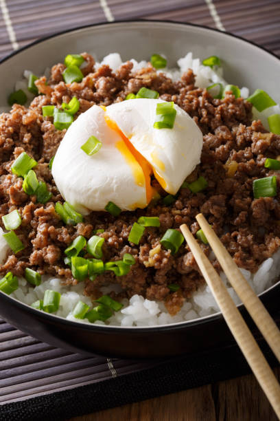 istock Japanese spicy beef Soboro with egg benedict, rice and green onion close-up. vertical 1037984558