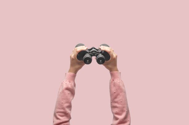 Woman with binoculars on retro pink background Woman with binoculars on retro pink background, looking through binoculars, journey, find and search concept. telescope lens stock pictures, royalty-free photos & images
