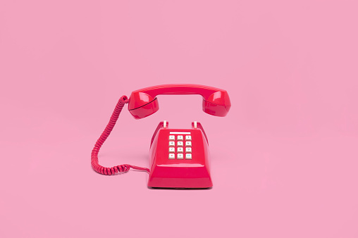 Teléfono retro color rosa sobre fondo rosa photo