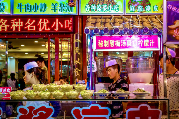 ciotole di noodles in vendita tra luminosi segni al neon allo xian muslim street market nella provincia di shaanxi, cina - shaanxi province immagine foto e immagini stock