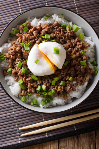 istock Beef Soboro with egg poached, rice and green onion close-up. Vertical top view 1037999868