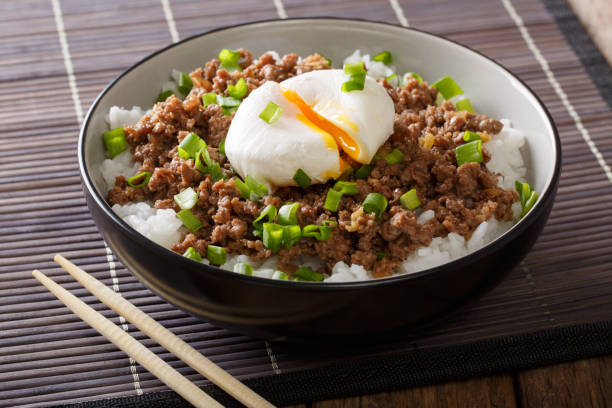 Delicious breakfast: spicy stewed minced meat with poached egg and rice close-up. horizontal
