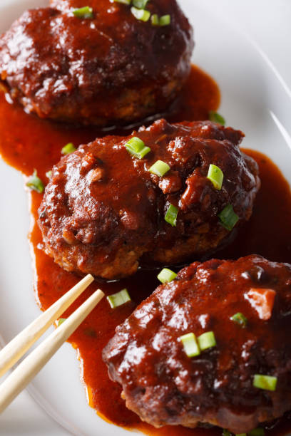 istock Japanese food: hamburg steak or hambagu with a spicy sauce on a plate macro. vertical 1038002564