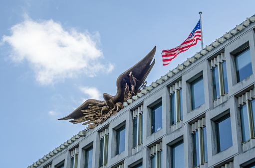 Eagle and flag on top of the former US Embassy building in Grosvenor Square, Mayfair, London.  The building was designed by American architect Eero Saarinen and completed in 1960.