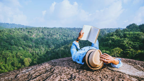 アジア人旅行は休日でリラックスします。スリープ リラックス岩の崖に本を読む。夏の山 - writing diary nature ideas ストックフォトと画像