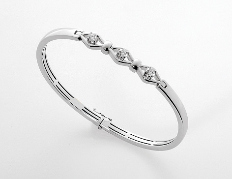 Simple stylish silver or platinum diamond bracelet or bangle with three faceted gemstones isolated on white