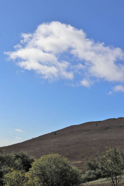 istock Fluffy white clouds in blue sky over hilltops 1038033620