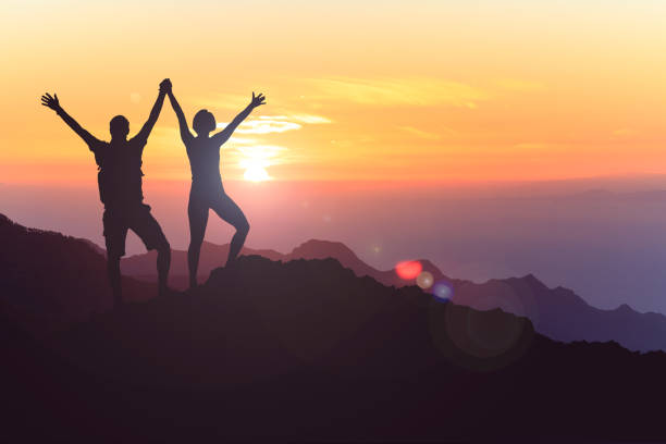 Happy couple celebrate, reaching life goal and success Successful couple achievement climbing or hiking, business concept with man and woman celebrating with arms up raised, outstretched outdoors. Motivational and inspirational silhouette landscape. black couple sunset stock pictures, royalty-free photos & images