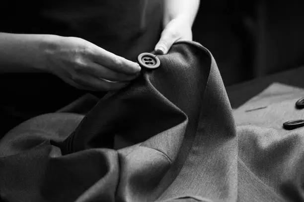 Sewing the buttons to the jacket. Tailor atelier - handmade exclusive clothes making and repair, private business, creative occupation concept
