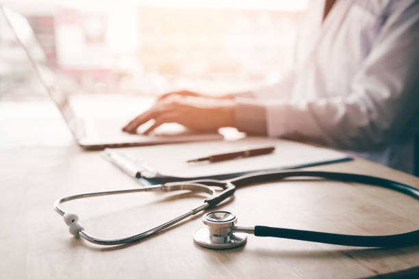 istock Stethoscope and background doctor using laptop at desk in clinic working on computer at room office. 1038044714