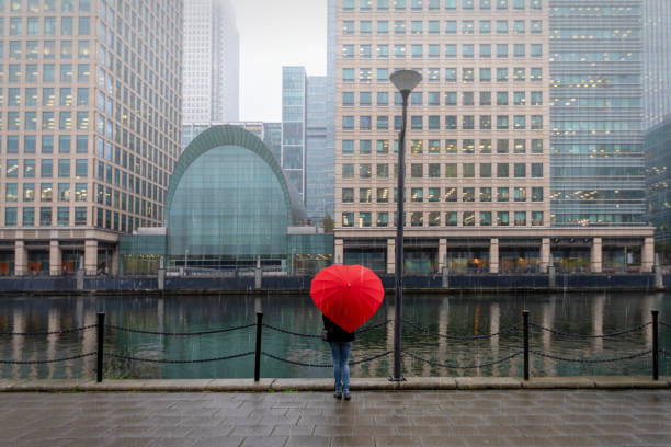 mujer de rojo, en forma de corazón paragüeros en london canary wharf - london england thames river storm rain fotografías e imágenes de stock
