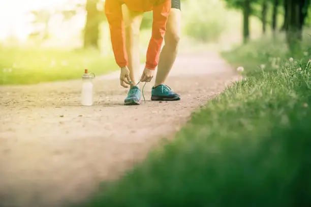 Woman runner tying sport shoes. Walking or running legs, autumn adventure and exercising outdoors. Motivation and inspiration fitness concept outside.