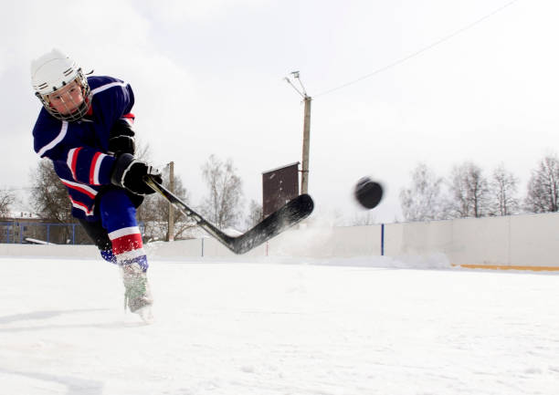der junge spielt hockey auf eine straße eisbahn. ein junge auf eine eisbahn spielt hockey. - winter sport team sport hockey puck sport stock-fotos und bilder