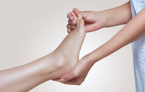 the doctor-podiatrist does an examination and massage of the patient's foot - reflexology pedicure massaging human foot imagens e fotografias de stock