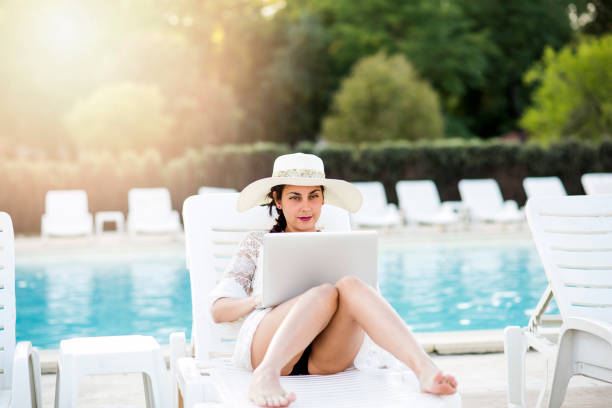 istock Woman working with laptop by the pool 1038075524